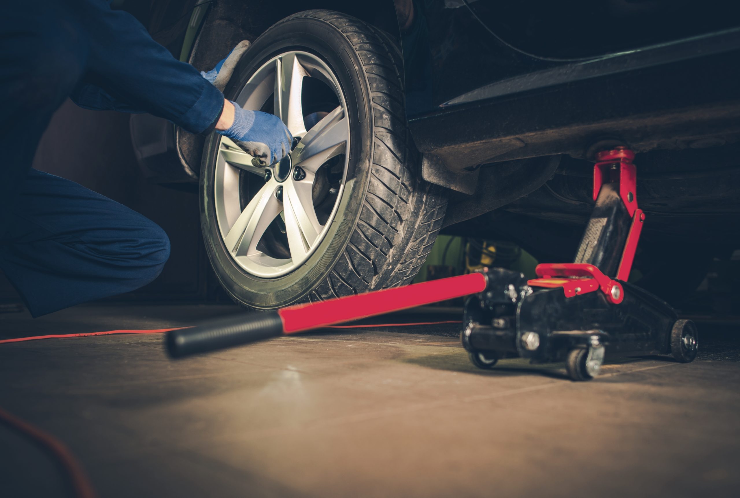 A mechanic performing a tire rotation using a jack.