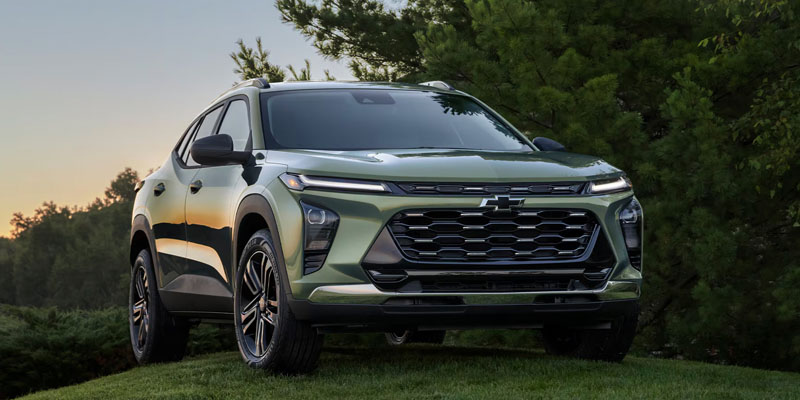 2026 Chevy Trax SUV parked on grass with trees at sunset.